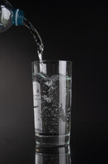 Pouring soda water into glass on a black background