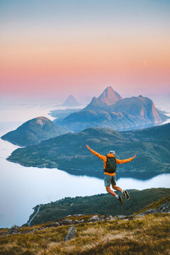 Man jumping enjoying mountains view travel solo in Norway active adventure vacations, tourist backpacker hiking healthy lifestyle freedom awakening concept dreamy sunset islands and sea landscape
