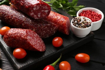 Different smoked sausages and products s on black wooden table, closeup