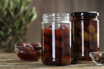 Pickled olives and spices on wooden table, closeup