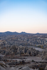 Panoramic view of Cappadocia’s unique rock formations and valleys at dusk, under a soft gradient sky. The surreal volcanic landscape highlights the natural wonders of central Turkey.