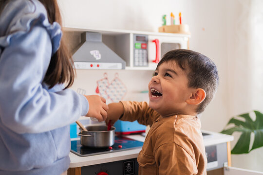 Two happy children playing with toy kitchen set, cooking and having fun together