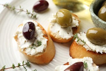 Delicious sandwiches with cream cheese and marinated olives on light table