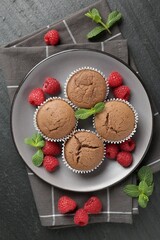 Delicious muffins with raspberries and mint on dark textured table, top view