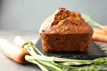 Tasty carrot cake and vegetables on grey textured table, closeup