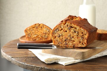 Cut homemade carrot cake with nuts and knife on wooden table, closeup
