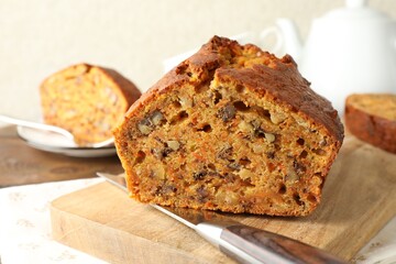 Cut homemade carrot cake with nuts and knife on table, closeup