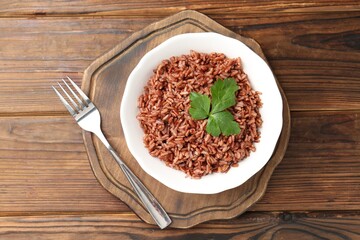 Delicious brown rice with parsley served on wooden table, top view