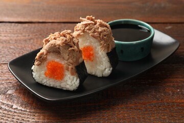 Tasty onigiri (Japanese rice balls) with tuna served on wooden table, closeup