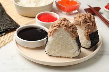 Tasty onigiri (Japanese rice balls) with tuna served on white marble table, closeup