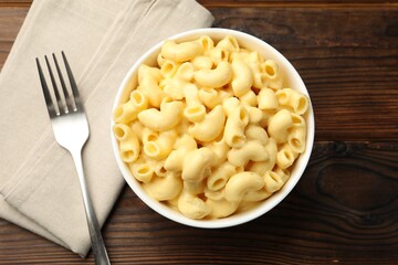 Delicious macaroni and cheese served on wooden table, top view