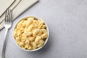 Delicious pasta with cheese sauce and fork on grey table, flat lay. Space for text