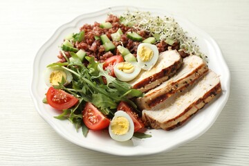 Delicious salad with brown rice on white wooden table, closeup