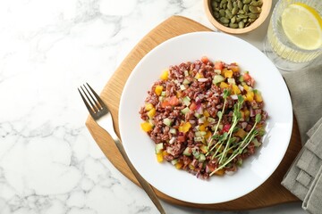 Tasty salad with brown rice served on white marble table, flat lay
