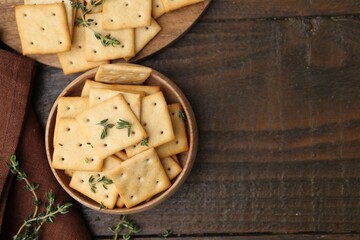 Tasty salty crackers with thyme on wooden table, flat lay. Space for text