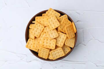 Tasty salty crackers on white textured table, top view
