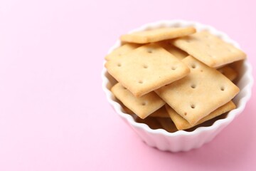 Tasty salty crackers on pink background, closeup. Space for text
