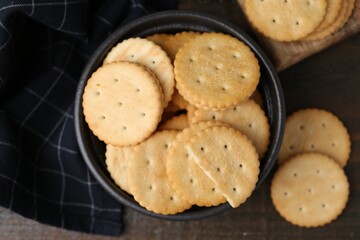 Tasty salty crackers on wooden table, flat lay