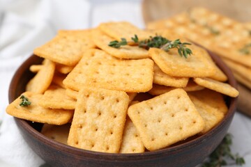 Tasty salty crackers and thyme on white table, closeup