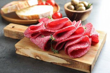Slices of delicious sausage with thyme served on grey table, closeup