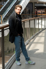 Fashionable man posing in modern shopping center during daytime