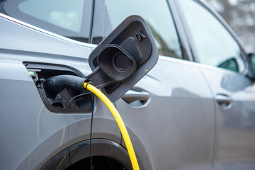 Naklejka premium Electric vehicle charging at a public station during daylight hours, showcasing modern technology and sustainability