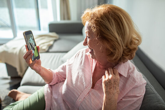 Smiling senior woman having video call on smartphone with friend at home