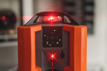 Laser level tool in focus on construction site with bright red laser line for alignment during building projects