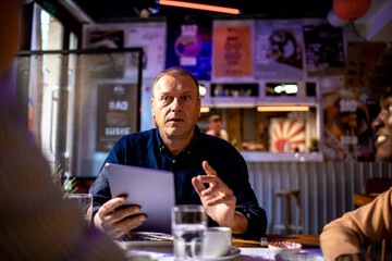 Businessman talking while ordering on tablet at sushi restaurant table