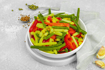 Vibrant frozen vegetable mix with yellow and green beans, red bell peppers, corn. Frosty texture