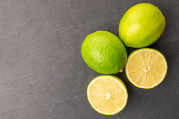 Sour juicy limes on slate stone, close-up, top view.