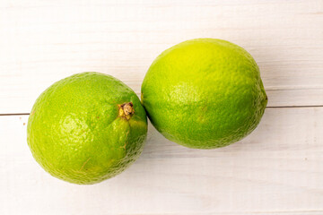 Sour juicy limes on a wooden table, close-up, top view.
