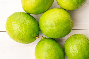 Sour juicy limes on a wooden table, close-up, top view.