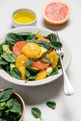 Fresh grapefruit avocado orange spinach salad in bowl. Healthy salad on gray background top view