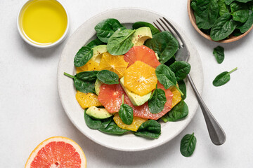 Fresh grapefruit avocado orange spinach salad in bowl. Healthy salad on gray background top view