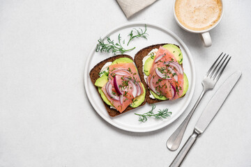 Smoked salmon avocado sandwich on light background. Black whole grain bread, avocado, salted salmon and dill for healthy breakfast