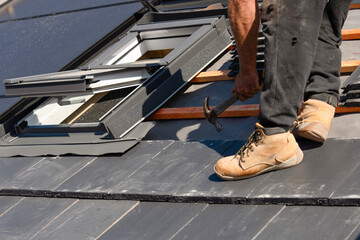 Builder installs roof window on home rooftop with tools and materials