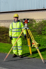 Surveyor working outdoors with surveying equipment in construction area