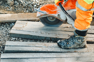 Builder using petrol concrete cutter saw to cut materials