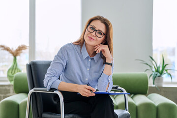 Portrait of professional psychologist therapist woman with clipboard in office