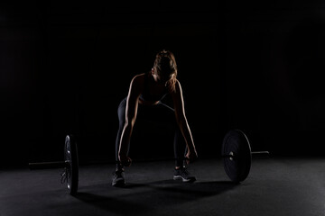 Young woman preparing to lift a heavy barbell in gym