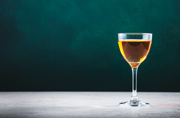 French calvados brandy in glass on dark green background