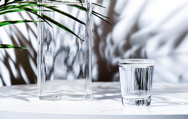 Vodka in glass and bottles of strong drink on white background, hard light