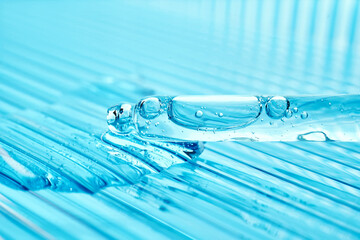 Serum in a pipette on a blue ribbed background.