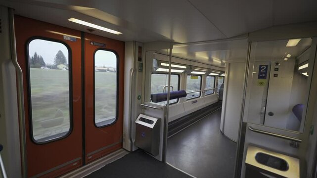 Modern interior of a Swiss double-decker train shows the first floor with standing space, toilet access, and wide windows for scenic views. Functional design ensures passenger comfort and mobility. 