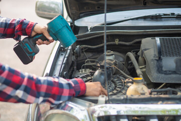 The man is checking the engine and condition of car to fix it properly and safely before traveling long distances. The man is checking condition of the car and the engine before traveling for safety.