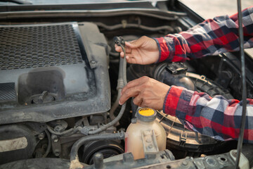 The man is checking the engine and condition of car to fix it properly and safely before traveling long distances. The man is checking condition of the car and the engine before traveling for safety.