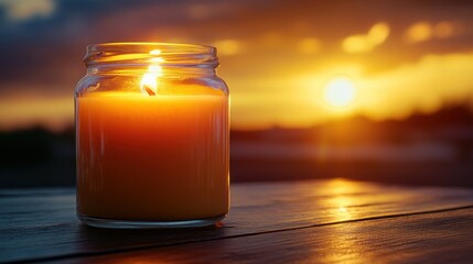 A candle flame glows warmly against a sunset backdrop