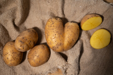 A rustic composition featuring whole and halved potatoes beautifully arranged on a textured burlap...