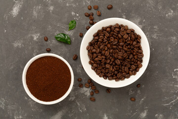 Roasted coffee beans with leaves on concrete background,top view